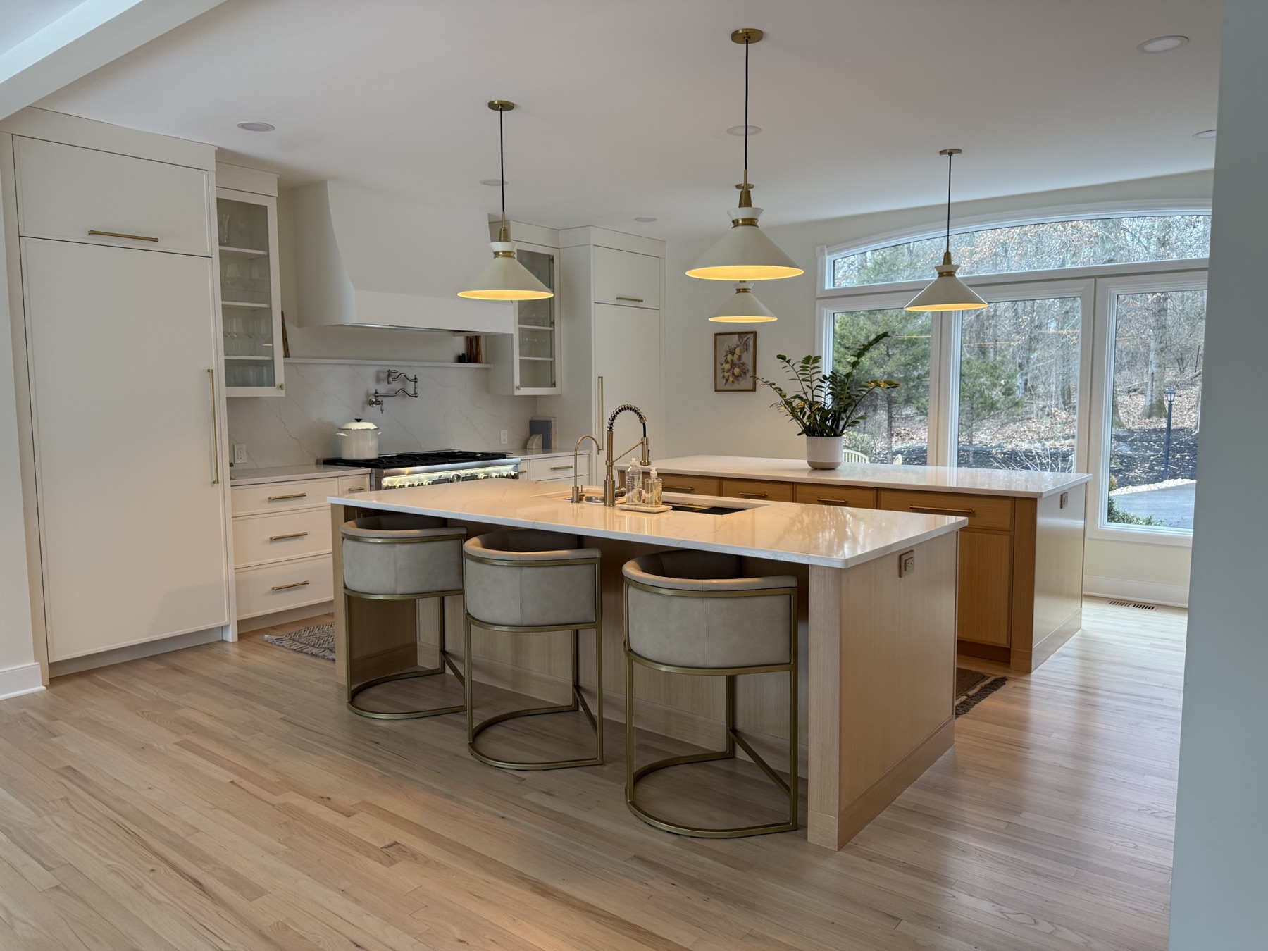 Bright renovated kitchen with large island, pendant lighting, and natural wood tones